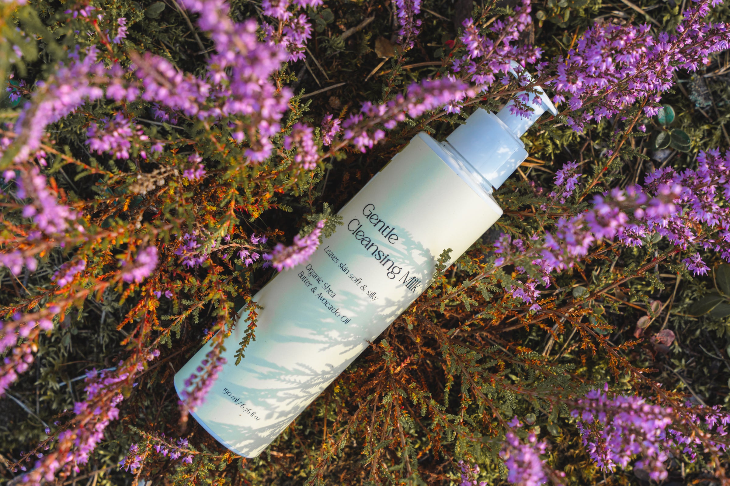 Kaiora skincare bottle labeled 'Gentle Cleansing' on a bed of purple flowers